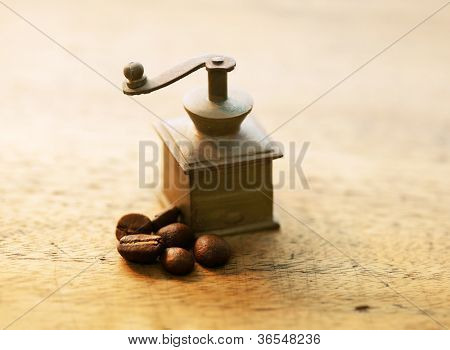 โรงสีขนาดเล็กทองเหลืองกาแฟและเมล็ดกาแฟบนโต๊ะเก่า