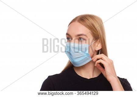 Blond Young Woman Wearing Medical Mask Adjusting It With Her Hands Close Up Isolated White Backgroun