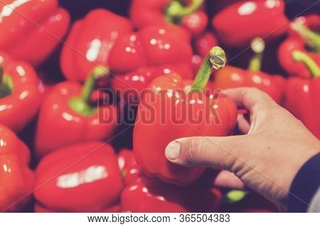 A Man Chooses Red Bell Peppers In A Grocery Store, At The Market. Hand Take The Pepper From A Vegeta