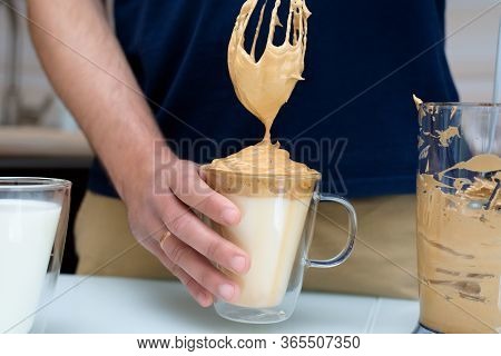 A Man In The Kitchen Is Preparing Dalgona Coffee, Whipped With A Mixer. The Process Of Making Dalgon