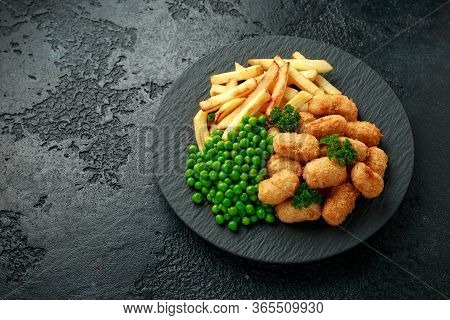 Crispy Battered Scampi Nuggets Served On Slate Plate With Potato Chips And Green Peas