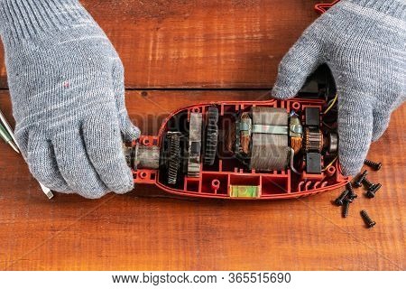 Technician Repairs Old Electric Drill On Brown Wooden Table