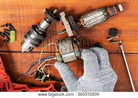 Technician Repairs Old Electric Drill On Brown Wooden Table