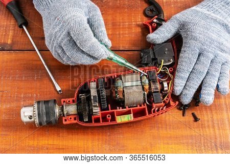 Technician Repairs Old Electric Drill On Brown Wooden Table