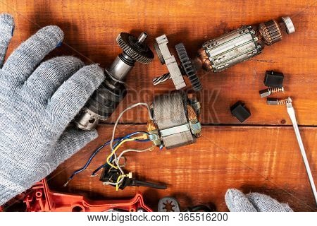 Technician Repairs Old Electric Drill On Brown Wooden Table