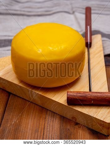 One Small Head Of Dutch Baby Gouda Cheese In Yellow Wax Close Up