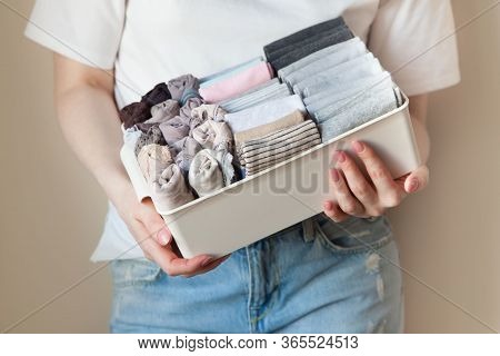 The Girl Is Holding A Basket, A Box With Vertically Folded Things. Cleaning In The Wardrobe, Clearin