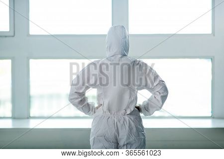 Medical Worker In Protective Clothing Standing With Her Back To The Camera, Hands On Her Waist