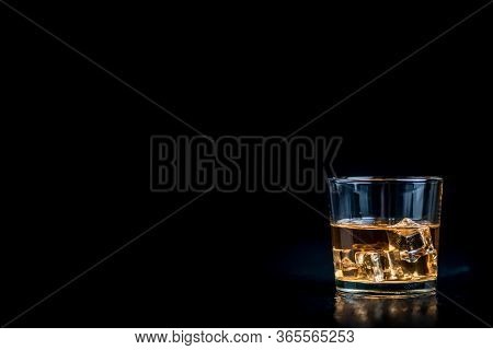 Whisky, Whiskey, Bourbon Or Cognac With Ice Cudes On Black Stone Table