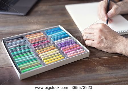 Person Painting With A Pastel Crayon Chalk On A White Sheet Of Paper With Pallette Of Pastel Chalks 