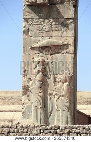 Ancient wall with bas-relief with king walking under an umbrella, Persepolis, Iran. UNESCO world heritage site