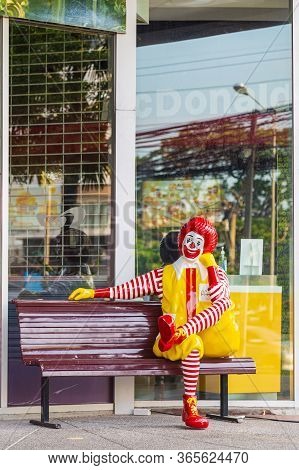 Nontaburi, Thailand- May 07, 2020 : Ronald-mcdonald Mascot Sitting On Wooden Bench In Front Of Mcdon