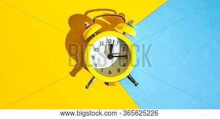 Yellow Vintage Alarm Clock On A Blue And Yellow Background With Selective Focus, Copy Space For Text