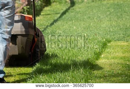 Man Moves With Lawnmower Mows Green Grass