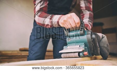 The carpenter process the wood by the belt sander