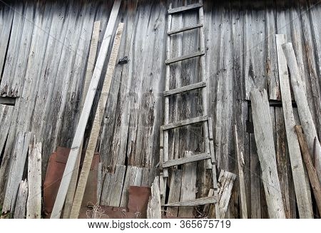 Old Weathered Wooden Ledder In Front Of Barn Almost Ruined. Background And Rural View