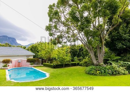 Exterior Of Upmarket Wealthy Suburban Mansion House With Landscaped Garden And Swimming Pool