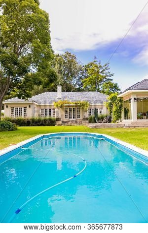 Exterior Of Upmarket Wealthy Suburban Mansion House With Landscaped Garden And Swimming Pool