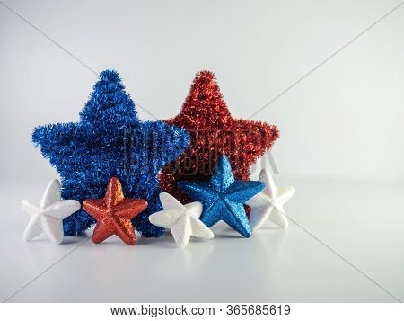 Red, White And Blue Sparkly And Tinsel Stars Standing Up On A White Background.  Patriotic Decor For