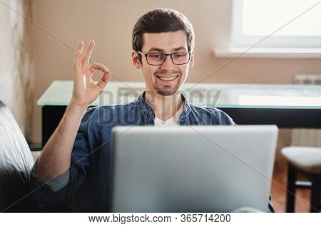 Happy European Man In Glasses Sitting At Home With Laptop, Making Video Call To Distant Friend And S