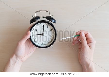 Woman Holds Negative Ovulation Test And Alarm Clock. Female Fertility Biological Clock Concept. Not 