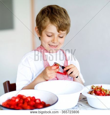 Little Blond Kid Boy Helping And Making Strawberry Jam In Summer. Funny Child Cleaning Berries And P