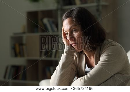 Bored Adult Woman Looking Away Sitting On The Sofa At Night At Home