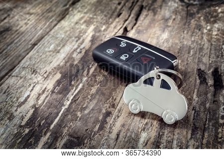 Car shape keyring and keyless entry remote on wood background