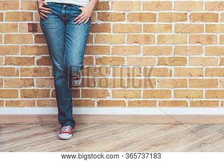 Woman Legs In Jeans And Red Sneakers, Woman Standing In Front Of Brick Wall, Fashion Concept