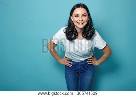 Young Woman In The Studio On A Blue Background Conveys Different Emotions. Beautiful Woman In Jeans 