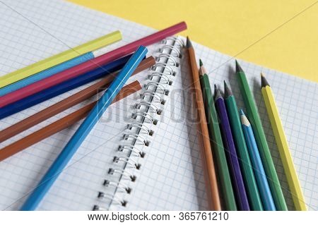 School Supplies On Yellow. Bright Back To School Background. Notepad And Stack Of Colorful Pencils. 