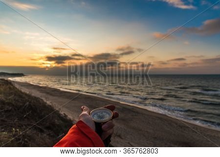 First-person View Of A Female Hand With A Compass On A Background Of A Beautiful Sea Landscape. The 