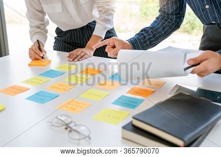 Young Business Workers Posting With Sticky Notes Stickers Reminders  Creative Brainstorming At Board