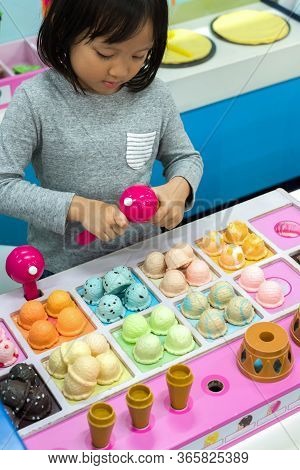 Cute Asian Child, Kid Role Playing Scoop Ice Cream In The Toy Ice Cream Shop At Indoor Amusement Par