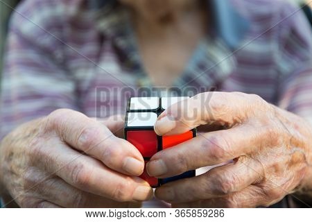 Closeup Of An Elderly Man Using A Rubix Type Cube Puzzle As Therapy For His Diminished Mental Capaci