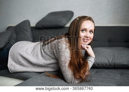Close-up Portrait Of Young Smiling Confident Female In Gray Home Interior, Hugge Style, Modern Trend
