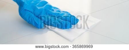 Surface cleaning against spreading of coronavirus person wearing gloves with antibacterial disinfecting wipe wiping glass table. banner panoramic background.