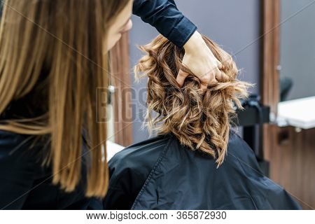 Female Hairdresser Chacking Womans Hairstyle In Beaury Salon, Close Up.