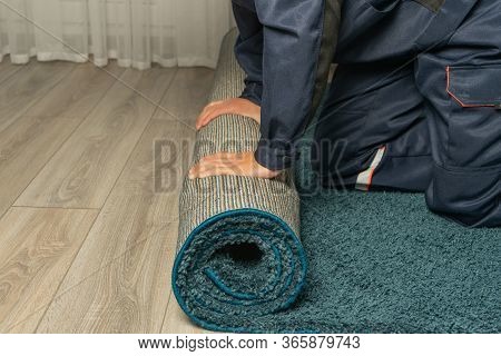 Close Up Of Male Hands Rolling Carpet. Help With Relocation Or Moving, Services Of A Porter Or Handy