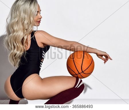 Beautiful Sexy Fitness Blonde Woman In Black Swimsuit, High Sport Socks And Sneakers Sitting With Ba