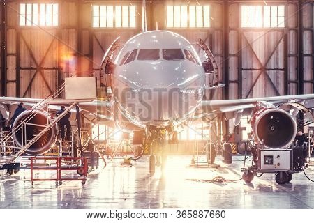 Airplane Under Repair In The Aerospace Hangar In The Background Of The Gate And Bright Sunlight
