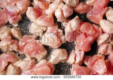 Small Pieces Of Pork Meat Are Fried In A Pan In Olive Oil. Close Up Selective Focus