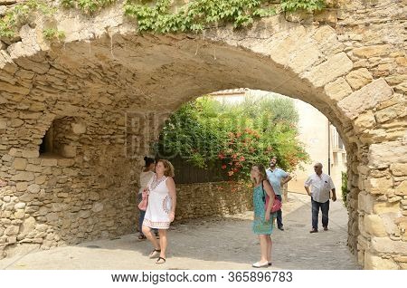 Peratallada, Spain - July 25, 2017: People Under Stone Arch At Cobbled Street Of The Medieval Villag