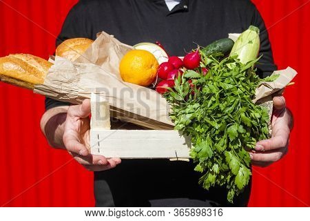 A Box With Fresh Vegetables And Fruits In Male Hands On A Blocky Background.