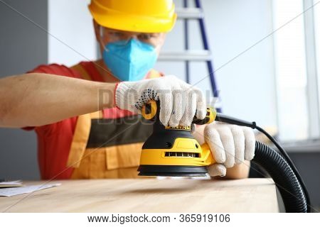 Close-up Of Male Worker Holding Sander Machine And Working With Wood. Handyman Wearing Protective Ye