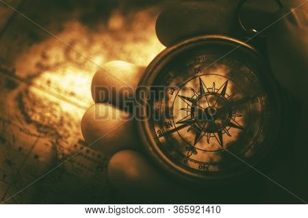 Close Up Of Caucasian Male Hand Holding Golden Compass And Map Laying On Table.
