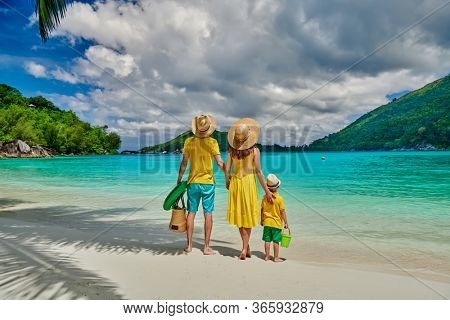 Family on beach, young couple in yellow with three year old boy. Summer vacation at Seychelles. Port Launay, Mahe. 