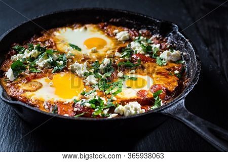 Shakshouka - Middle eastern traditional dish with poached eggs in tomato sauce with feta cheese