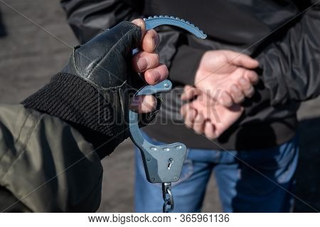 Arrest Of A Criminal, A Police Officer Puts Handcuffs On The Hands Of A Bandit