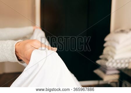 closeup of a young caucasian man making the bed with white bedsheets